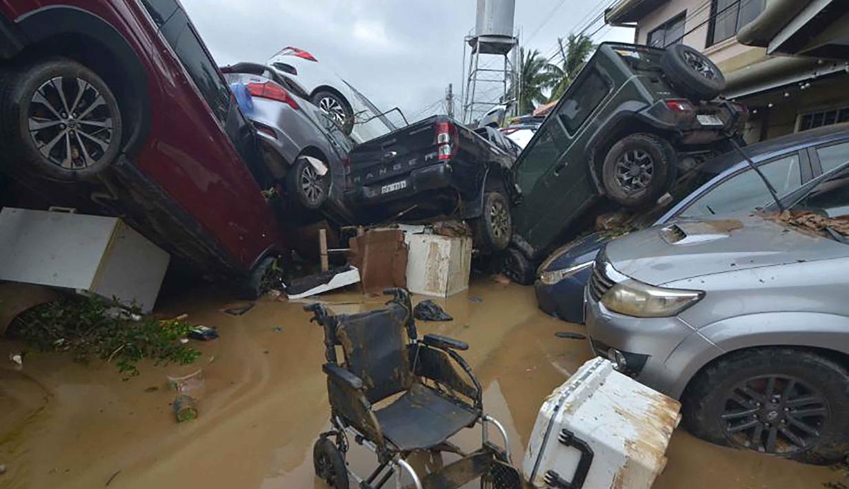 Pemandangan umum menunjukkan kendaraan-kendaraan yang tertimbun banjir akibat hujan deras yang dibawa oleh Topan Kalmaegi di sebuah permukiman di Kota Cebu, Filipina tengah, pada Selasa 4 November 2025. Sementara itu, lebih dari 150 ribu warga telah dievakuasi dari wilayah timur sebelum topan mendarat. (Alan TANGCAWAN/AFP)