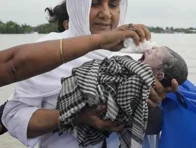 Diluwara Begum, seorang bidan, menggendong bayi yang baru lahir setelah membantu persalinannya di atas perahu di atas Sungai Brahmaputra, di negara bagian Assam, India timur laut, Rabu, 3 Juli 2024. (AP Photo/Anupam Nath)