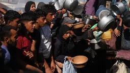 Warga Palestina menunggu bantuan gula dan beras di dapur umum di Khan Younis, Jalur Gaza selatan, Jumat, 31 Oktober 2025. Mereka datang dengan membawa panci dan piring kosong serta harapan mendapat bantuan makanan. (AP Photo/Abdel Kareem Hana)