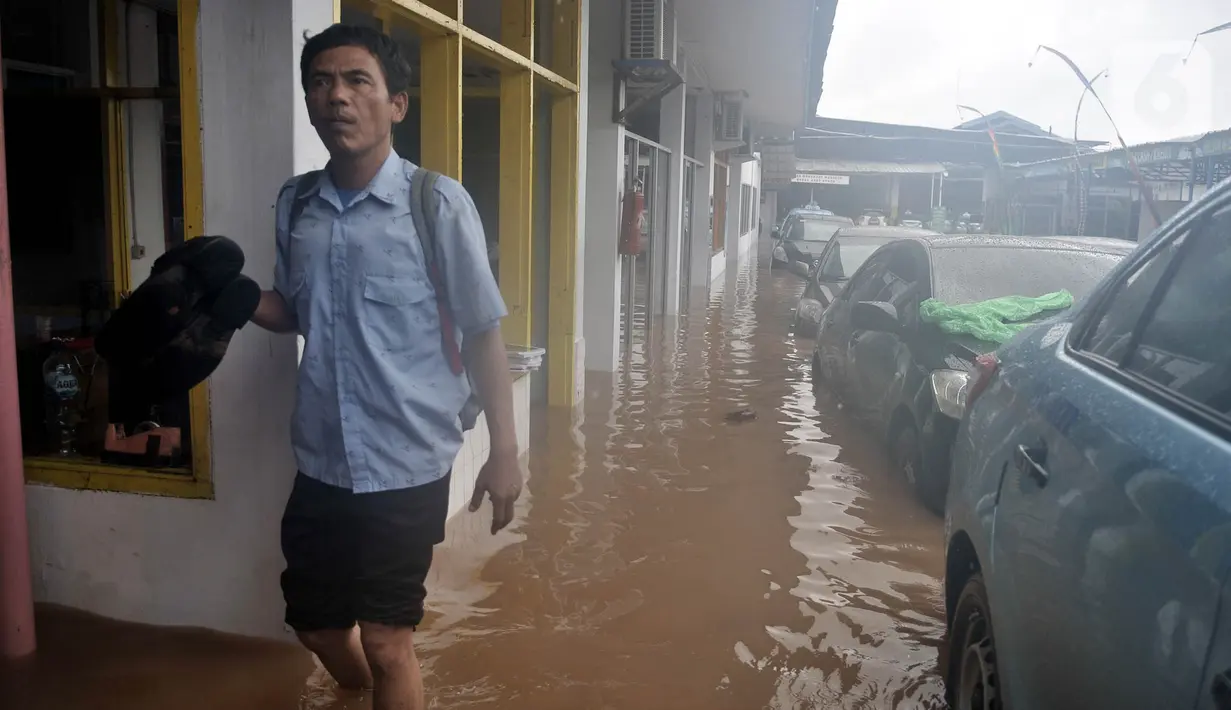 Seorang sopir melintasi banjir di Pool Blue Bird Kramat Jati, Jakarta, Rabu (1/1/2020). Akibat banjir setinggi hingga leher orang dewasa tersebut pool berhenti operasi dan sopir terpaksa diliburkan hingga waktu yang belum ditentukan. (merdeka.com/Iqbal S. Nugroho)