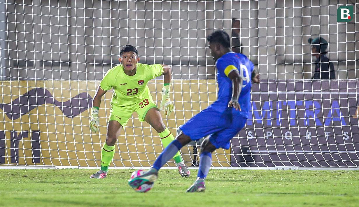 Kiper Timnas Indonesia, Ikram Al Giffari (kiri) bersiap menerima tendangan pemain Maladewa, Shanaan Rashaad pada laga Grup F Kualifikasi Piala Asia U-20 2024 di Stadion Madya, Senayan, Jakarta, Rabu (25/09/2024). (Bola.com/Bagaskara Lazuardi)