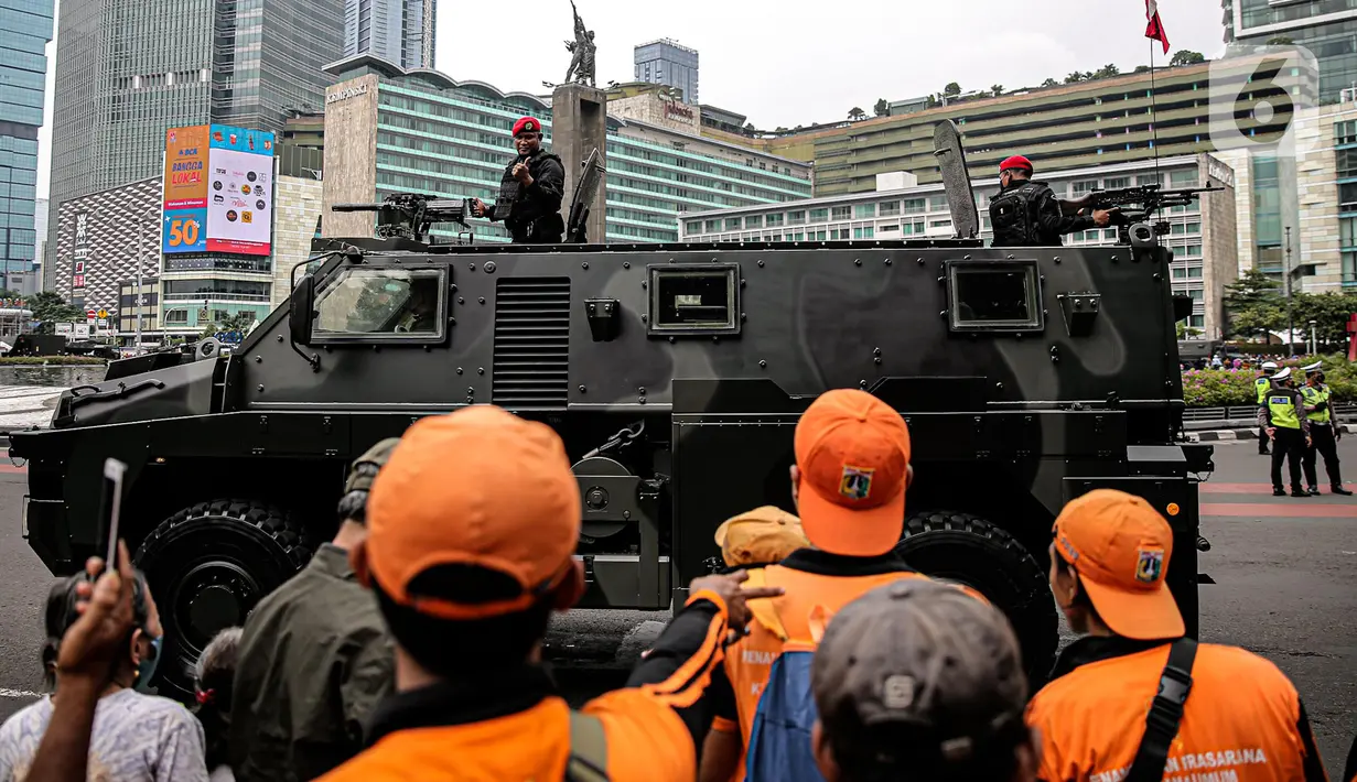 Tentara memberikan isyarat kepada warga dari atas alat utama sistem senjata (alutsista) milik TNI saat perayaan HUT ke-77 TNI di Bundaran HI, Jakarta, Rabu (5/10/2022). Kegiatan yang diikuti oleh seluruh kesatuan jajaran TNI ini dalam rangka menyambut HUT ke-77 TNI. (Liputan6.com/Faizal Fanani)