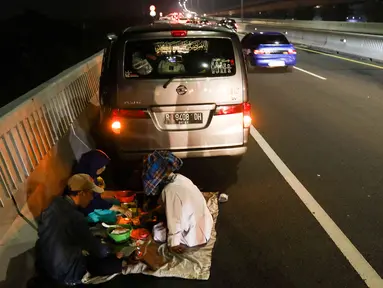 Sejumlah pemudik melaksanakan sahur dan istirahat  di bahu jalan Tol MBZ, Tambun, Kabupaten Bekasi, Jawa Barat, Kamis (20/4/2023). (Liputan6.com/Herman Zakharia)