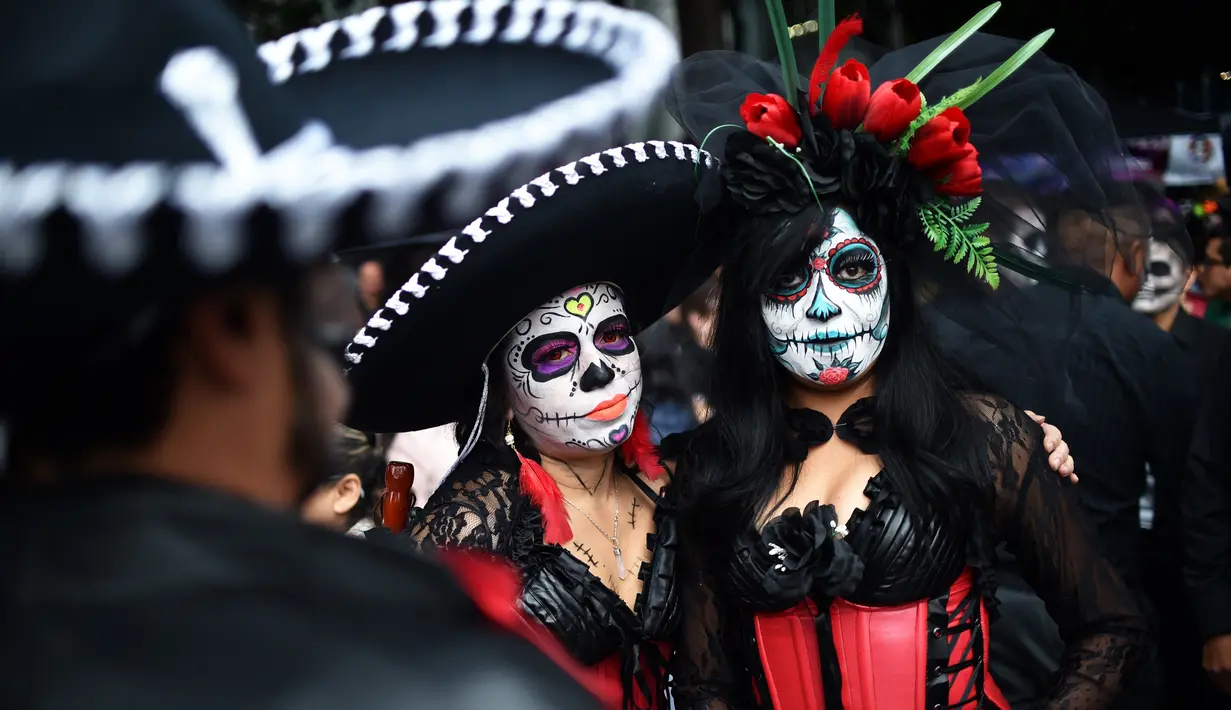 Orang-orang berpakaian seperti "Catrina" ambil bagian dalam parade Hari Orang Mati di Reforma Avenue, Mexico City, 21 Oktober 2018. Banyak orang yang menggenakan kostum tengkorak dan hiasan serba tongkorak yang memenuhi jalanan. (RODRIGO ARANGUA/AFP)