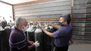 Orang-orang memeriksa tekanan oksigen di tempat pengisian ulang oksigen di Baghdad, Irak (7/7/2020). Pabrik pengisian oksigen milik pemerintah di Irak meningkatkan pengisian tabung oksigen dan gas cairnya untuk memenuhi permintaan rumah sakit di tengah terus bertambahnya infeksi COVID-19. (Xinhua)