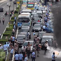 Asap hitam mengepul dari aksi bakar ban yang dilakukan sopir taksi yang melakukan demo di tol dalam kota, Mampang, Jakarta, Selasa (22/3). Para sopir taksi juga memblokade jalan sehingga kendaraan tak bisa melintas. (Liputan6.com/Johan Tallo)