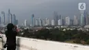 Seseorang mengambil gambar suasana gedung bertingkat di kawasan Jakarta, Jumat (17/6/2022). Jakarta meneruskan posisinya di jajaran atas kota berkualitas udara buruk di dunia hari ini, Jumat 17 Juni 2022, setelah kemarin mencatat hal serupa. (Liputan6.com/Angga Yuniar)