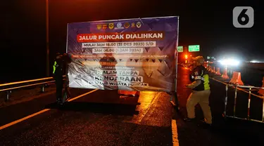 Petugas Tol Jasa Marga memasang papan penutupan jalur Puncak di pintu keluar tol Gadog, Bogor, Jawa Barat, Minggu (31/12/2023). (merdeka.com/Arie Basuki)