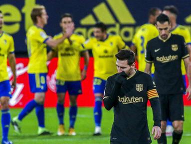 Striker Barcelona, Lionel Messi, tertunduk lesu usai ditaklukkan Cadiz pada laga Liga Spanyol di Stadion Ramon Carranza, Minggu (6/12/2020). Barcelona takluk dengan skor 1-2. (AP/Alvaro Rivero)