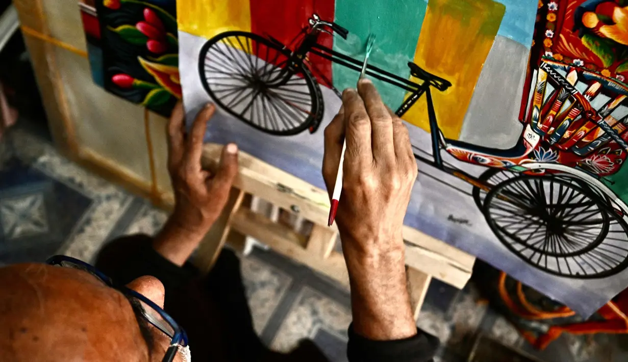 Seniman becak, Hanif Pappu sedang mengerjakan sebuah lukisan di tokonya di Dhaka. (Munir UZ ZAMAN/AFP)