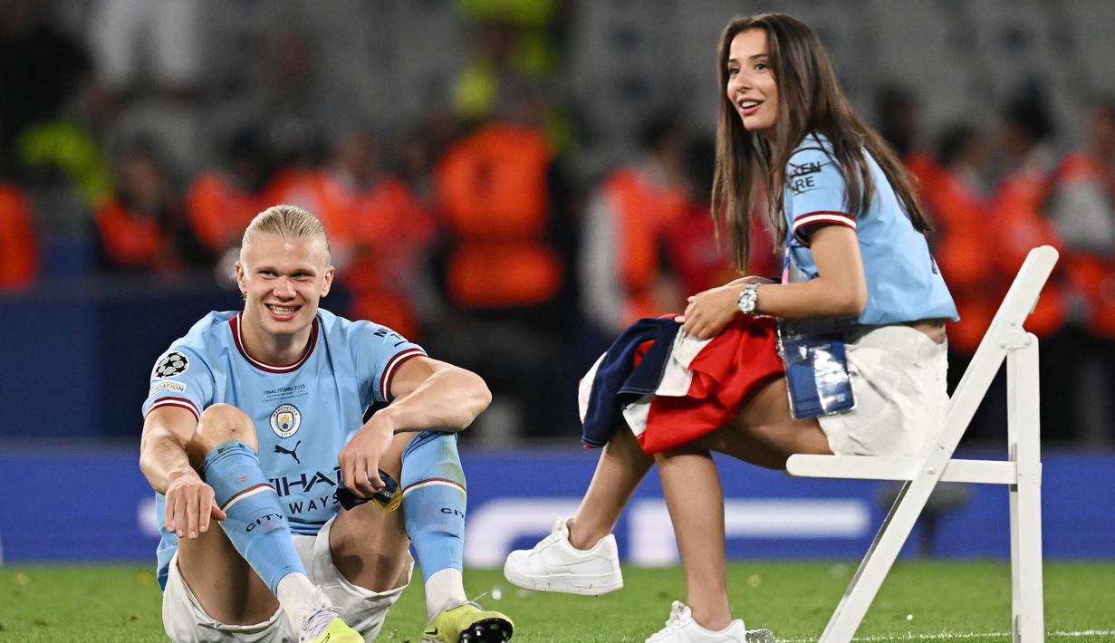 Pemain Manchester City, Erling Haaland, bersantai dengan kekasihnya Isabel Haugseng Johansen saat perayaan gelar juara Liga Champions di Ataturk Olympic Stadium, Istanbul, Minggu (11/6/2023). Erling Haaland tampil luar biasa dan mampu meraih treble winner di musim perdananya bersama City. (AFP/Paul Ellis)