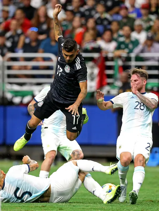 Pemain Meksiko Jesus Corona melompati pemain Argentina Leandro Paredes dalam laga persahabatan di Alamodome, San Antonio, Texas, Amerika Serikat, Selasa (10/9/2019). Argentina menang 4-0 atas hattrick Lautaro Martinez. (Edward A. Ornelas/Getty Images North America/AFP)