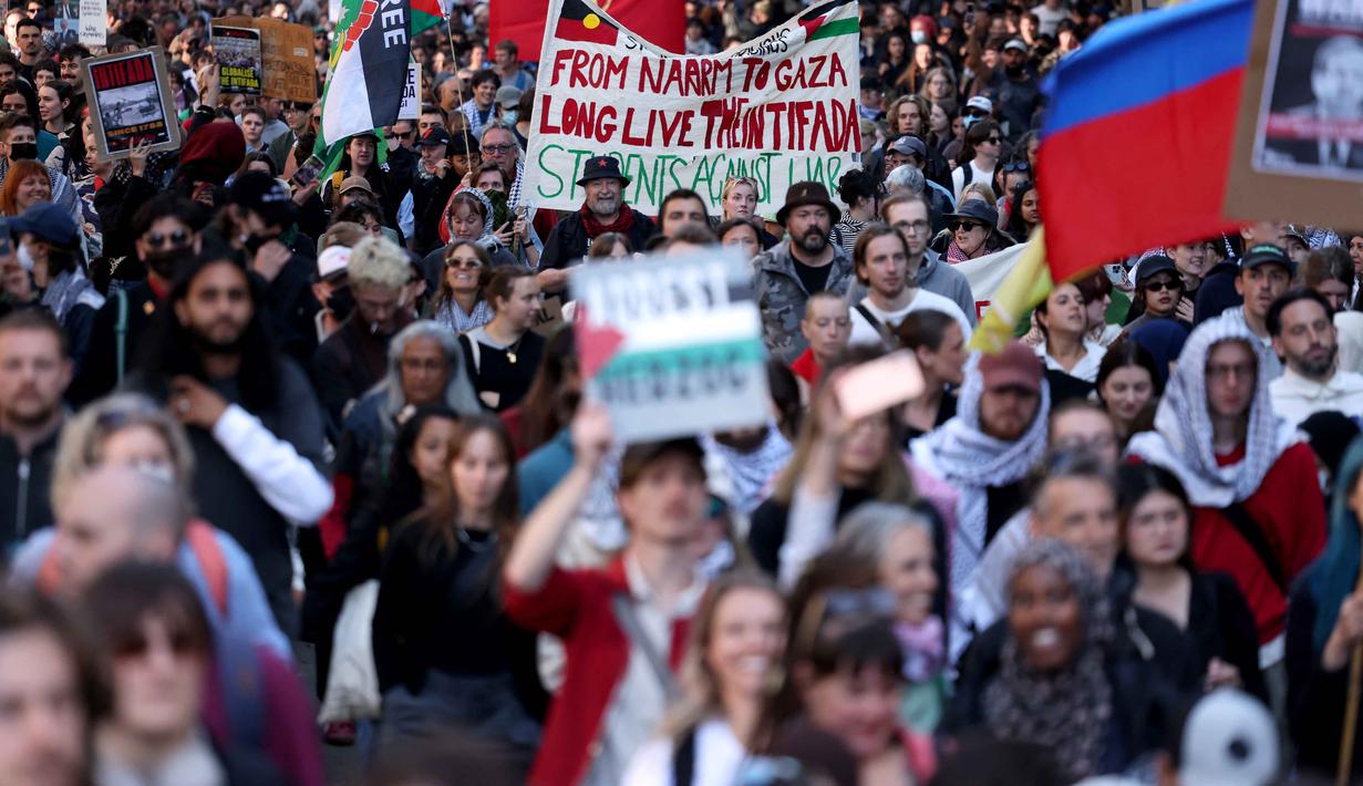Aksi tersebut menjadi rangkaian protes terakhir selama kunjungan empat hari Presiden Israel, Isaac Herzog, di Australia. Tampak dalam foto, para pengunjuk rasa memegang plakat dan bendera saat mereka berunjuk rasa selama kunjungan Presiden Israel, Isaac Herzog, di Melbourne, Australia, pada Kamis 12 Februari 2026. (MARTIN KEEP/AFP)