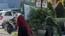 Dua wanita muslim berjalan melewati papan izin mendirikan bangunan (biru) di bekas lokasi bom Bali Sari Club di Kuta, Bali, Jumat (26/4). Perdana Menteri Australia Scott Morrison memprotes rencana pembangunan restoran di lahan bekas Sari Club yang merupakan lokasi pemboman Bali (SONNY TUMBELAKA/AFP)