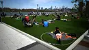 Orang-orang berusaha menjaga jarak dalam lingkaran putih saat bersantai di Domino Park, Brooklyn di Kota New York, Minggu (17/5/2020). Pengunjung taman berjemur dengan tetap menerapkan protokol penularan coorna Covid-19. (Photo by Johannes EISELE / AFP)