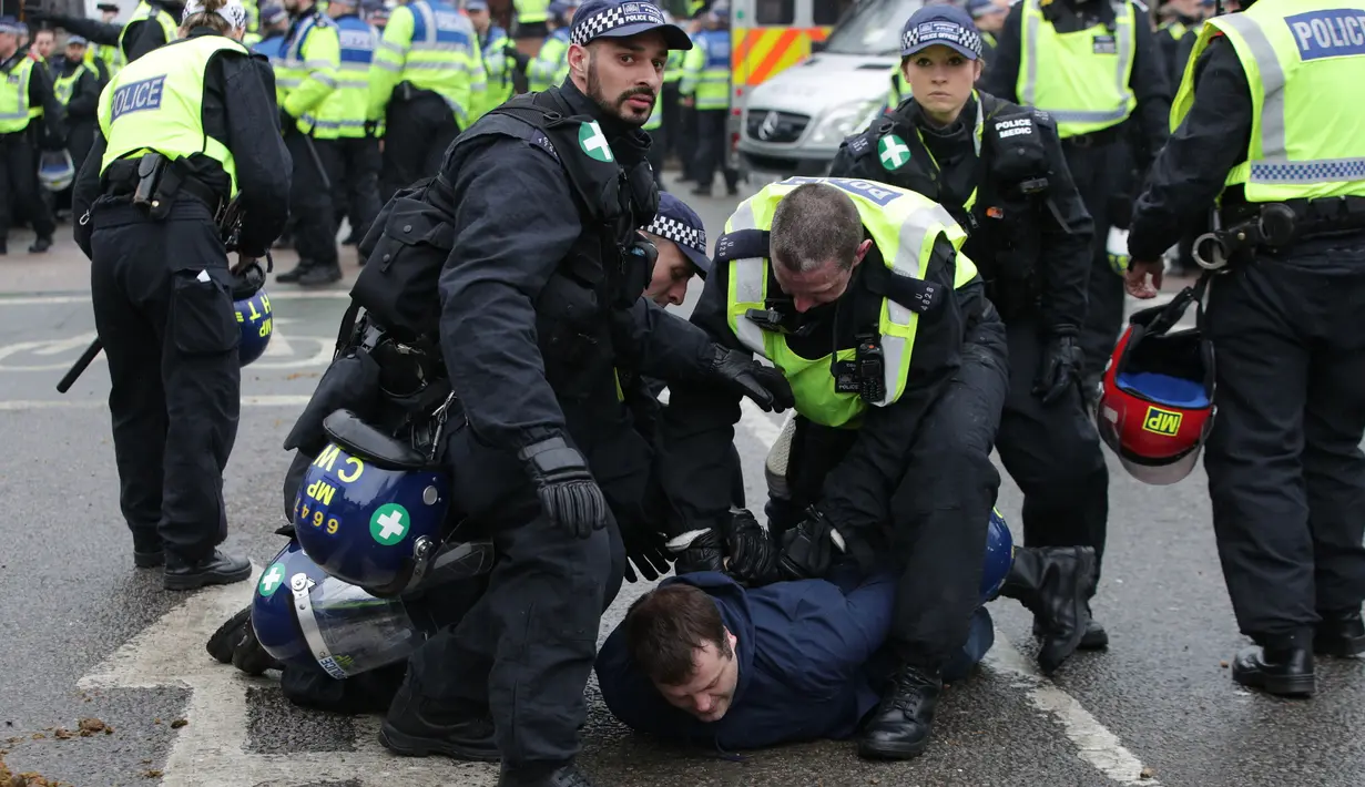 Petugas mengamankan seorang suporter saat terlibat bentrokan sebelum pertandingan perempat final Piala FA antara Tottenham Hotspur melawan Millwall di White Hart Lane, London, (12/3). (Yui Mok//PA via AP)