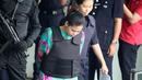 Tersangka Siti Aisyah asal Indonesia mengenakan rompi peluru saat dikawal polisi usai menjalani sidang pembunuhan kaka tiri Kim Jong-un, Kim Jong-nam di Departemen Kimia Malaysia, Petaling Jaya, Kuala Lumpur, (9/10). (AP Photo/Sadiq Asyraf)