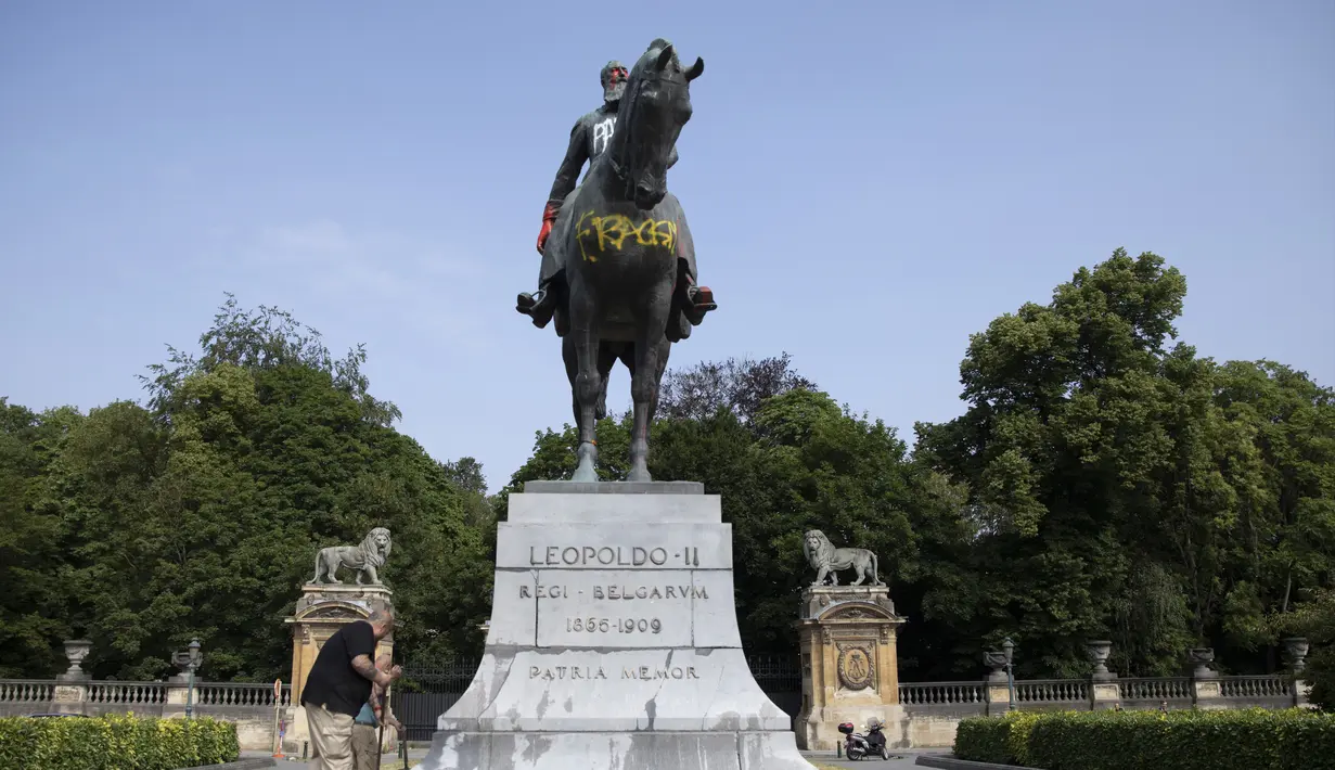 Sejumah pria membersihkan coretan pada patung Raja Belgia Leopold II di Brussel, Belgia, Rabu (10/6/2020). Di tengah protes dunia atas kematian George Floyd, patung Raja Leopold II dirusak karena pemerintahannya yang brutal ketika menguasai Kongo ratusan tahun silam. (AP Photo/Virginia Mayo)
