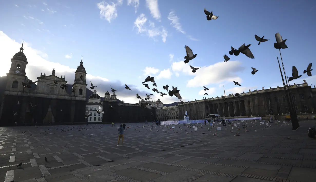 Merpati terbang di atas mainan yang mewakili anak korban kekerasan selama protes di alun-alun Bolivar di Bogota, Kolombia, Senin (30/11/2020). Ratusan mainan, boneka, dan action figure diletakkan di Bolivar Square untuk memprotes kekerasan terhadap anak-anak. (AP Photo/Fernando Vergara)