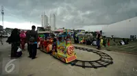 Sejumlah warga antre di dekat permainan kereta yang ada di areal RPTRA Kalijodo, Jakarta, Selasa (28/3). Sejumlah warga menghabiskan libur Hari Raya Nyepi dengan mengajak putera puterinya bermain di areal RPTRA Kalijodo. (Liputan6.com/Helmi Fithriansyah)