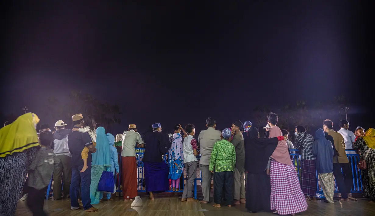 Warga menyaksikan gerhana bulan saat mendung di Surabaya pada 8 November 2022. Fenomena alam tersebut dapat disaksikan dengan mata telanjang. (AFP/Juni Kriswanto)