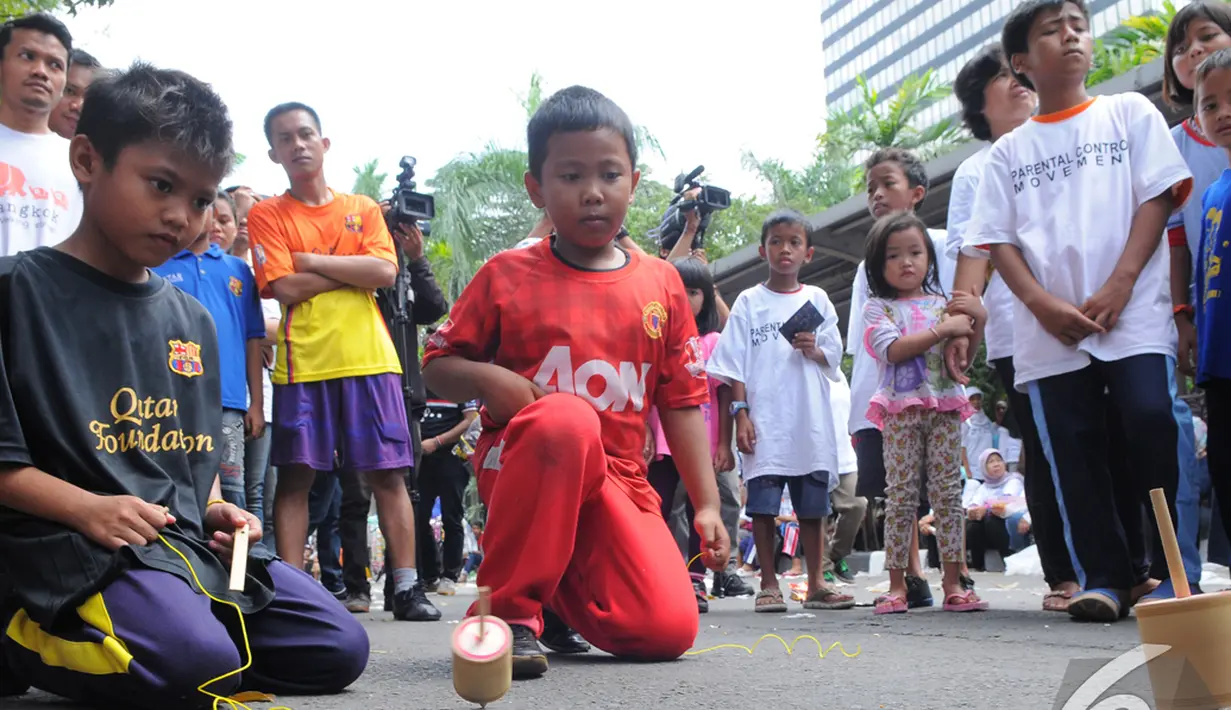 Para bocah asyik bermain gasing di acara "Save Our Children", Jakarta, Minggu (23/11/2014) (Liputan6.com/Faisal R Syam)