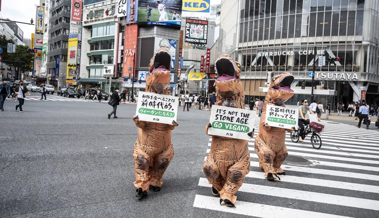 Aktivis kelompok hak hewan PETA mendesak orang untuk menjadi vegan selama protes di Tokyo, Jepang, Rabu (6/10/2021). Dalam aksinya, para aktivis mengenakan kostum dinosaurus. (CHARLY TRIBALLEAU/AFP)