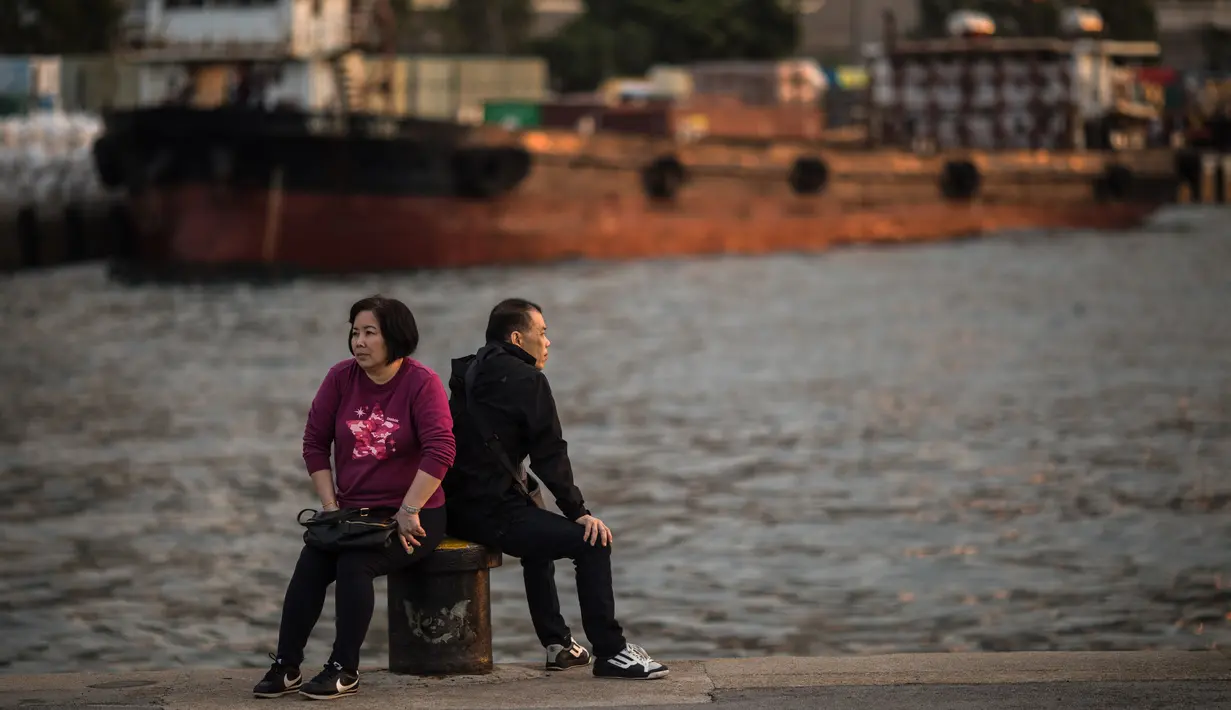 Pasangan lansia bersantai di dermaga umum di sebelah Pelabuhan Victoria di Hong Kong (3/3). Pemandangan yang spektakuler membuat pelabuhan ini menjadi daya tarik wisata utama Hong Kong. (AFP Photo/Dale De La Rey)
