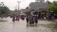 Ojek gerobak di Jalan Hasyim Ashari, Ciledug, Kota Tangerang, Banten saat banjir merendam. (Liputan6.com/Naomi Trisna)