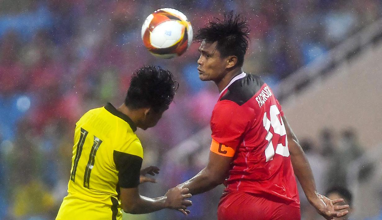 Pemain Timnas Indonesia, Fachruddin Aryanto, duel udara dengan pemain Malaysia, Muhammad Syafik, pada laga perebutan medali perunggu SEA Games 2021 yang digelar di Stadion My Dinh, Hanoi, Minggu (22/5/2022). (AFP/ Ye Aung Thu)