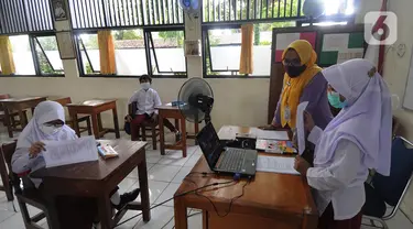 Murid kelas IV menunjukkan hasil tesnya kepada teman-temannya yang belajar online di rumah saat kegiatan belajar tatap muka di SDN Pondok Labu 14 Pagi di Cilandak, Jakarta Selatan, Jumat (4/6/2021). (merdeka.com/Arie Basuki)