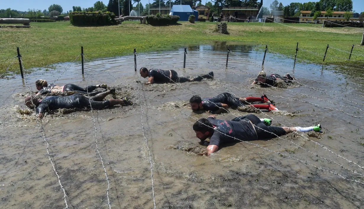 Peserta lomba melewati kawat berduri saat mengikuti "Legion Run" di Roma, Italia, Sabtu (13/4). Peserta harus melewati rintangan seperti dari lumpur, es dan kawat berduri dengan jarak tempuh 5 kilometer. (AFP PHOTO / Andreas SOLARO)