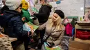 Pamela Anderson memberikan peralatan sekolah kepada seorang anak di pengungsian Grande-Synthe, Prancis (25/1). Selain itu Pamela juga bermain dan menghibur anak-anak yang berada di kamp pengungsian. (AFP/Philippe Huguen)