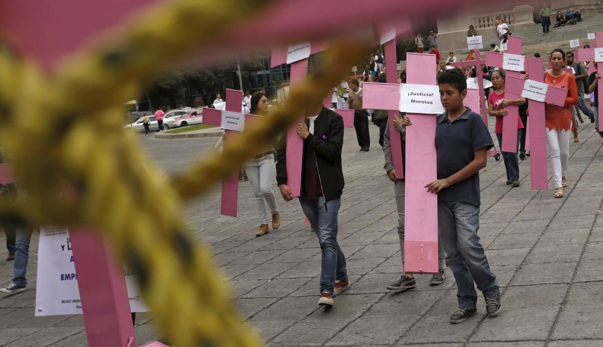Sejumlah orang membawa salib berwarna pink saat memperingati Hari Internasional untuk Penghapusan Kekerasan terhadap Perempuan di Meksiko, Rabu (25/11). Setiap tahunnya, kegiatan ini berlangsung dari tanggal 25 November. (REUTERS/Daniel Becerril)