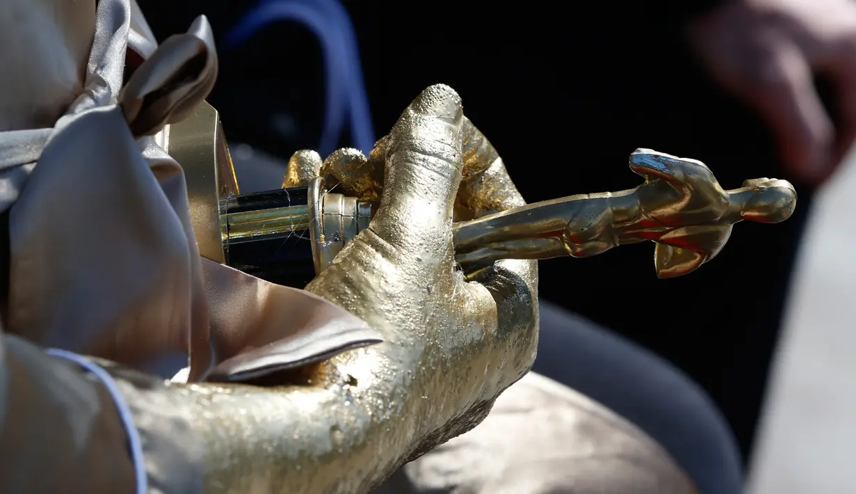 Detail patung piala Oscar yang dipegang oleh patung produser film, Harvey Weinstein ketika dipajang dekat lokasi ajang Academy Awards ke 90 di Hollywood, Kamis (1/3). Weinstein mengenakan jubah mandi dan duduk di sofa berwarna emas. (AP/Damian Dovarganes)