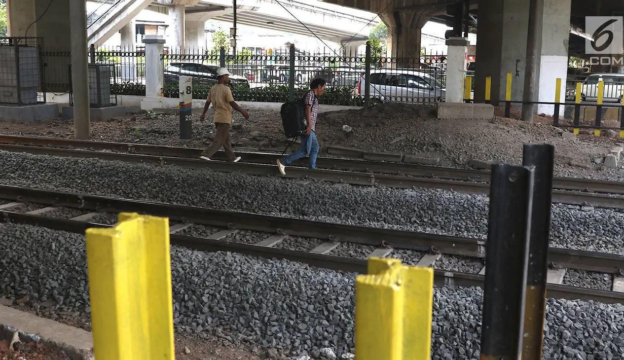 Pejalan kaki menyeberangi perlintasan kereta api di Tanjung Barat, Jakarta, Senin (7/1). Meskipun sering terjadi kecelakaan dan dipasangi pagar, pejalan kaki tetap melompati pagar dari pada menggunakan fasilitas JPO. (Liputan6.com/Immanuel Antonius)