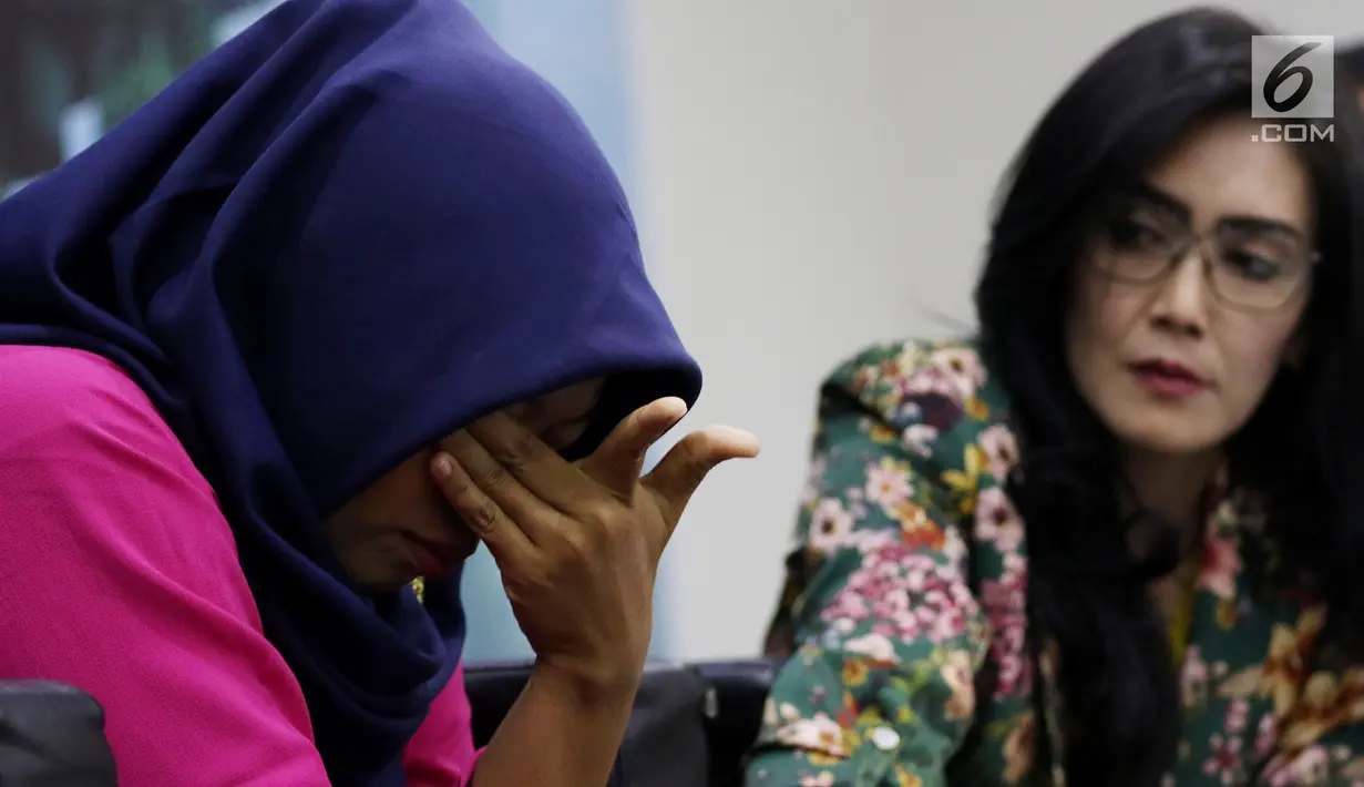 Terpidana kasus pelanggaran UU ITE Baiq Nuril (kiri) tertunduk sambil memegangi matanya saat berbicara dalam diskusi Dialektika Demokarasi di Kompleks Parlemen Senayan, Jakarta, Rabu (10/7/2019). Baiq berurai air mata saat berbicara di hadapan wartawan dan anggota dewan. (Liputan6.com/JohanTallo)