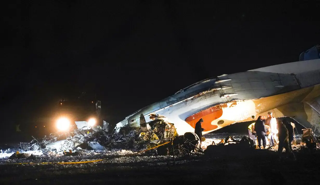Pekerja darurat bekerja di samping pesawat Antonov An-26 yang jatuh di Bandara Almaty, Kazakhstan, Sabtu (13/3/2021). Antonov An-26 merupakan pesawat transportasi militer buatan Rusia. (AP Photo/Vladimir Tretyakov)