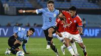 Gelandang Chile Marcelino Nunez, kanan, berbeut bola dengan gelandang Uruguay Manuel Ugarte  dalam Kualifikasi Piala Dunia 2026 zona CONMEBOL di Estadio Centenario, Sabtu (9/9/2023) pagi WIB. (AP Photo/Santiago Mazzarovich)