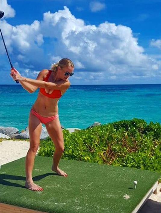 Petenis Denmark Caroline Wozniacki mengenakan bikini berwarna merah saat bermain golf di pinggir sebuah pantai. (Instagram/@carowozniacki)