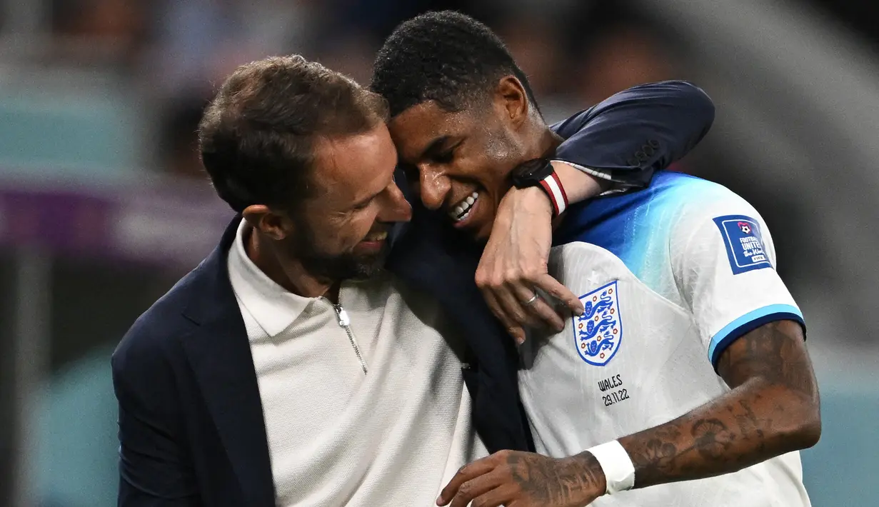 Striker Timnas Inggris, Marcus Rashford dipeluk pelatih Gareth Southgate usai ditraik keluar saat menghadapi Wales pada laga fase Grup B Piala Dunia 2022 Qatar di Ahmad Bin Ali Stadium, Doha (29/11/2022). Hingga kini Marcus Rashford total telah tampil dalam 51 laga bersama Timnas Inggris dengan torehan 15 gol dan 5 assist. Pada laga debutnya menghadapi Australia dalam sebuah laga persahabatan jelang Euro 2016 (27/5/2016), ia langsung mencetak satu gol dan membawa Inggris menang 2-1. (AFP/Paul Ellis)