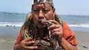 Seorang dukun Peru mencium ular selama ritual untuk menyambut tahun baru  di pantai Agua Dulce, Lima, Kamis (27/12). Ritual dimaksudkan untuk membawa kekuatan dan energi ke seluruh dunia sehingga ada kedamaian dan ketenangan. (AP/Martin Mejia)