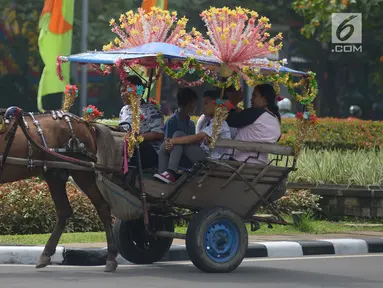 Pengunjung berkeliling naik delman hias di Monumen Nasional (Monas), Jakarta, Sabtu (15/6/2019). Sebelumnya delman hias tersebut dilarang kini beroperasi kembali, delman tersebut mengenakan tarif pada pengunjung bervariasi untuk berkeliling di luar IRTI Monas. (merdeka.com/Imam Buhori)