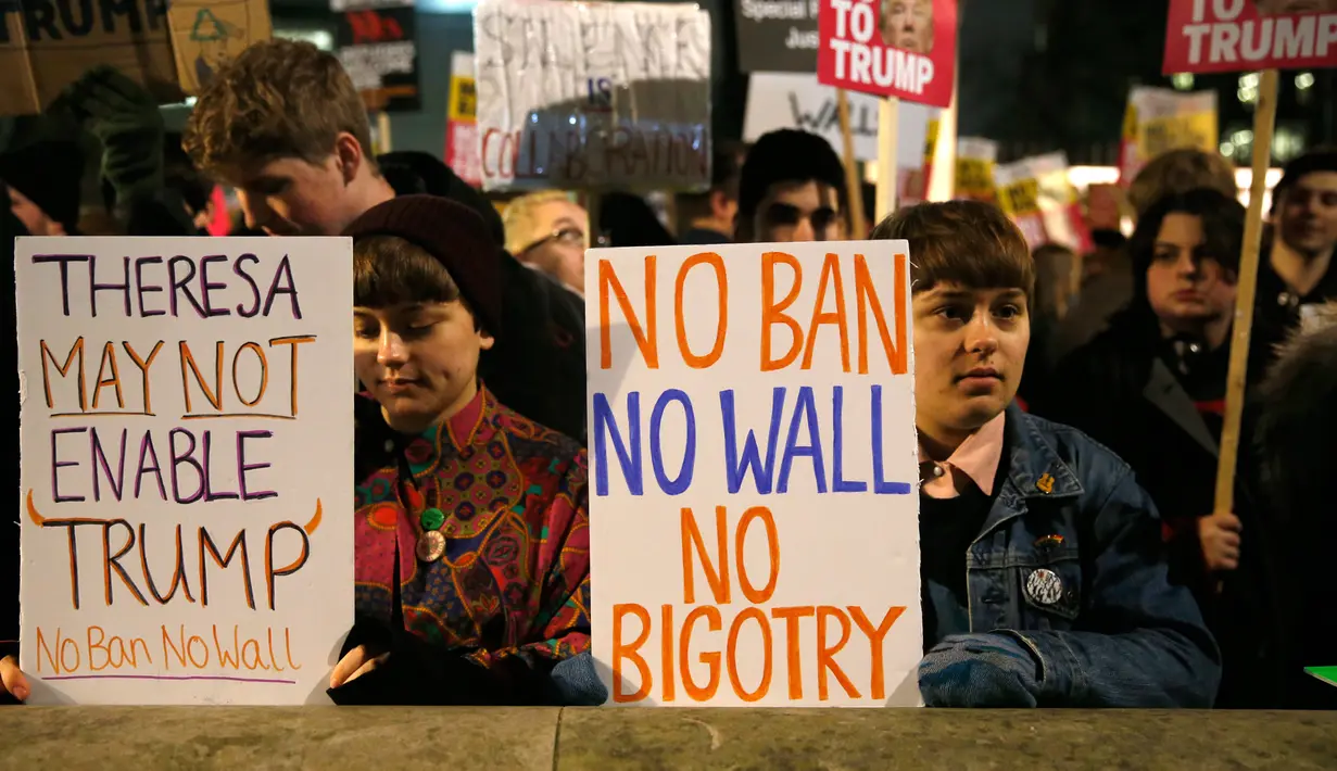 Demonstran membentangkan poster saat unjuk rasa di luar Downing Street, London, Senin (30/1). Mereka memprotes kebijakan Presiden AS Donald Trump yang melarang Muslim dari sejumlah negara memasuki Amerika Serikat. (AP Photo/Alastair Grant)