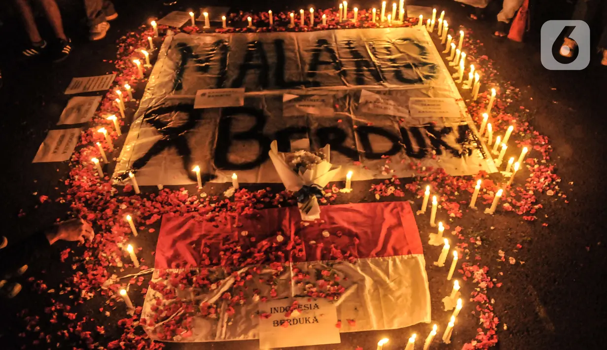 Massa yang tergabung dalam Ultras Garuda Jakarta mengikuti aksi menyalakan lilin dan tabur bunga untuk korban kerusuhan Stadion Kanjuruhan Malang di depan Stadion Gelora Bung Karno (GBK), Jakarta, Minggu (2/10/2022). Aksi tersebut sebagai aksi solidaritas antar suporter dan bentuk keprihatinan atas tragedi kerusuhan suporter sepak bola di Stadion Kanjuruhan Malang. (merdeka.com/Iqbal S Nugroho)