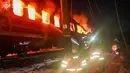 Menurut keterangan otoritas Ukraina, serangan ini menewaskan sedikitnya empat orang dan melukai dua lainnya. Tampak dalam foto yang diberikan dan dirilis oleh Layanan Darurat Ukraina pada 27 Januari 2026 ini, petugas medis Ukraina berdiri di samping gerbong kereta yang terbakar setelah serangan udara di lokasi yang tidak diungkapkan di wilayah Kharkiv, di tengah invasi Rusia ke Ukraina. (Handout/UKRAINIAN EMERGENCY SERVICE/AFP)