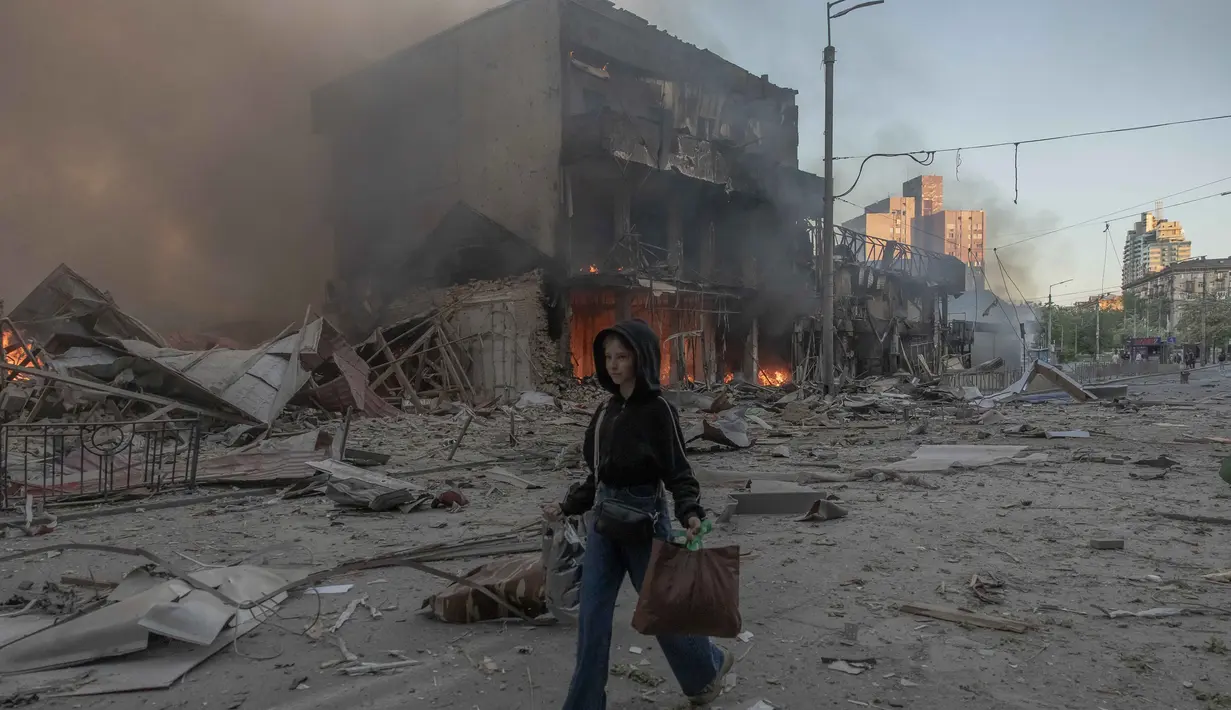 Seorang wanita berjalan di samping bangunan-bangunan yang rusak parah akibat serangan Rusia di Kyiv pada Minggu 24 Mei 2026, di tengah invasi Rusia ke Ukraina. (Roman PILIPEY/AFP)