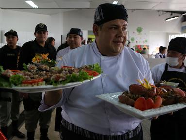 Narapidana membawa makanannya untuk dinilai oleh dewan juri dalam kompetisi kuliner 'INPE Mistura 2016' di penjara perempuan Chorrillos di Lima, Peru, Rabu (7/9). Sejumlah penjaga penjara memperhatikan dan mengawasi secara seksama. (REUTERS/Mariana Bazo)