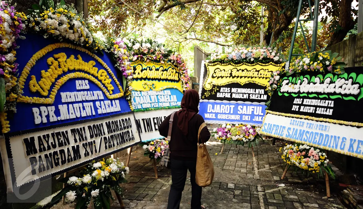 Pelayat melintasi karangan bunga duka cita wafatnya Maulwi Saelan di Al Azhar Syifa Budi, Jakarta, Selasa (11/10). Maulwi Saelan mantan penjaga gawang Timnas Indonesia era 50-60 dan mantan ajudan Presiden Soekarno. (Liputan6.com/Helmi Fithriansyah)