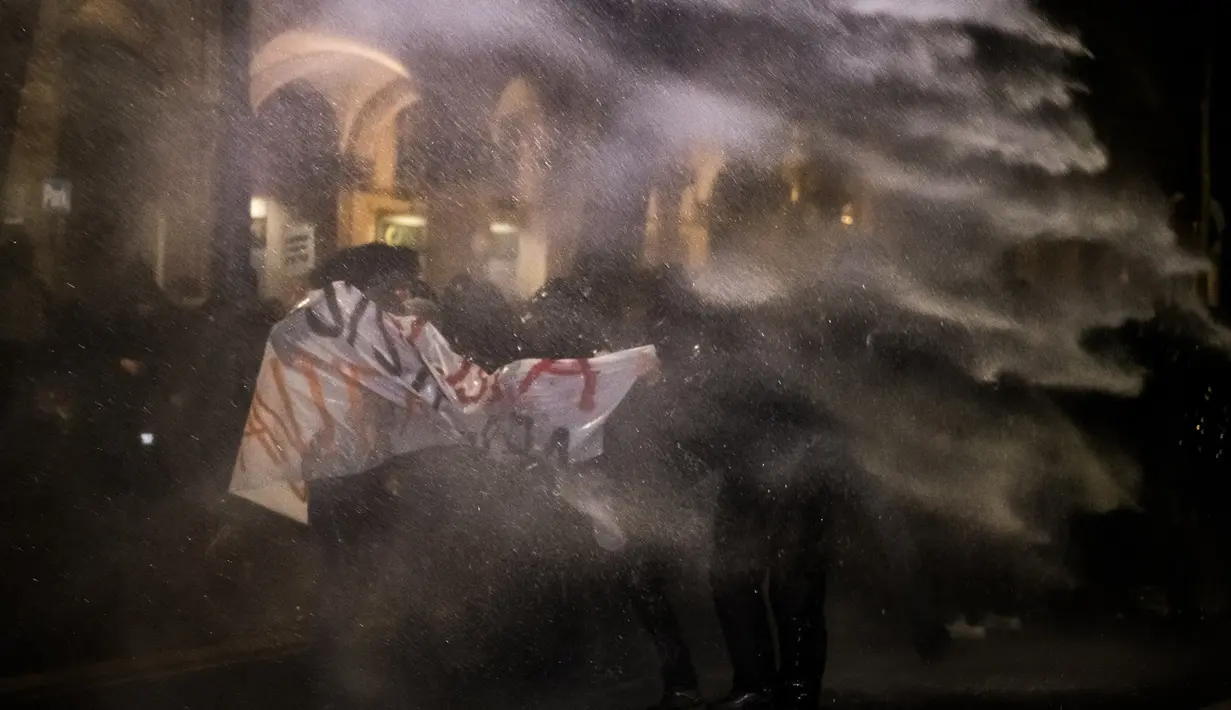 Petugas keamanan menembakan meriam air ke arah aktivis antifasis yang menggelar demonstrasi di Turin, Italia (22/2). Para aktivis menentang kampanye pemilihan yang diselenggarakan oleh gerakan sayap kanan Italia, CasaPound. (AFP Photo/Piero Cruciatti)